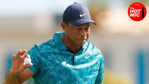 Tiger woods is holding a golf ball in a blue hat and green shirt at the hero world challenge.