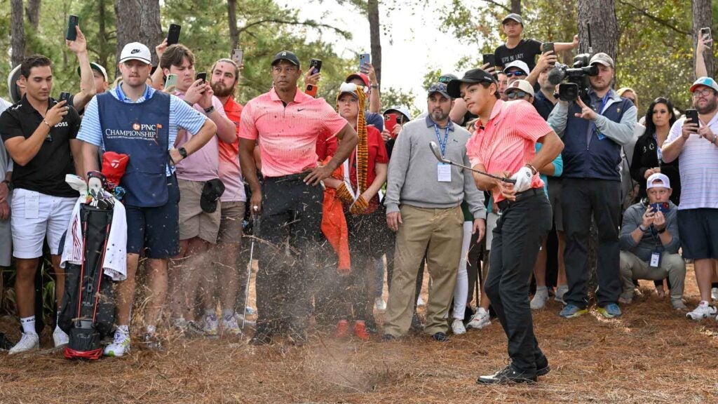Charlie Woods hits a shot as Tiger Woods watches at 2023 PNC Championship