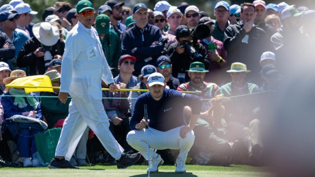 patrick cantlay squats over putt at Masters with crowd in background