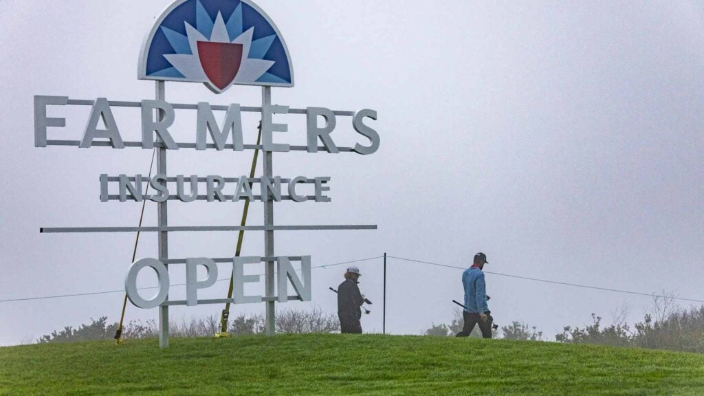 Pro golfers walk past large sign during practice at 2024 Farmers Insurance Open