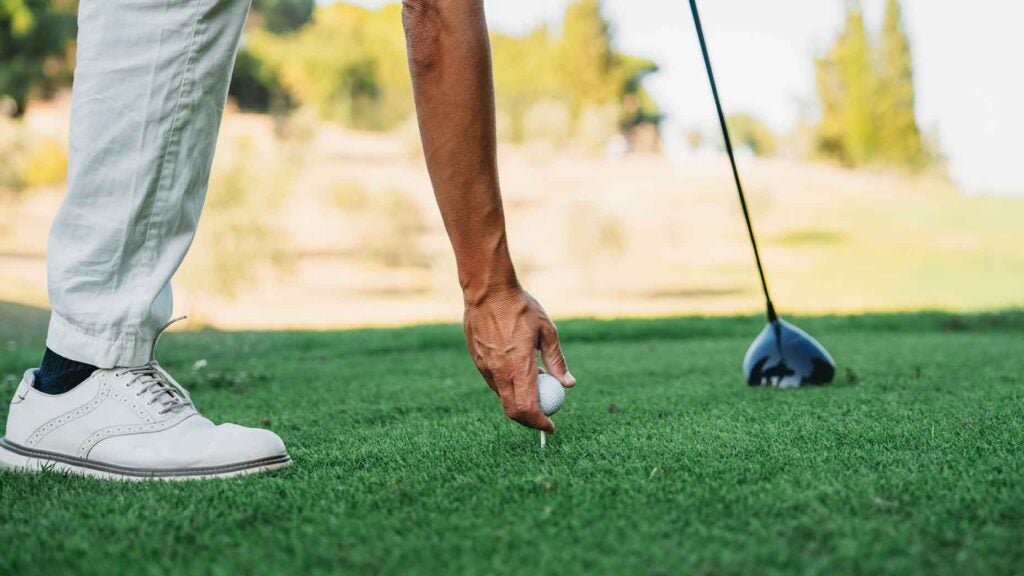 A golfer is preparing for strike. Close up detail of his hand holding the ball.
