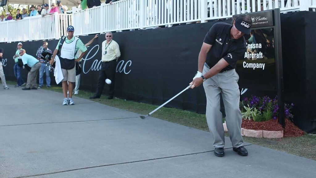 phil mickelson hits a wedge shot from the cart path during the wgc-cadillac championship