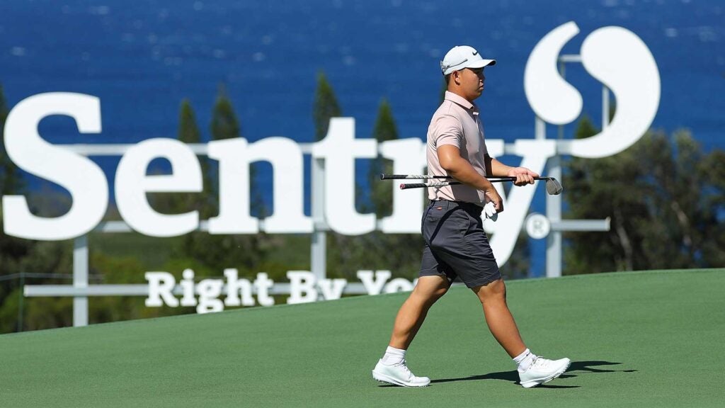 Tom Kim walks on Kapalua course in front of Sentry signage and ocean