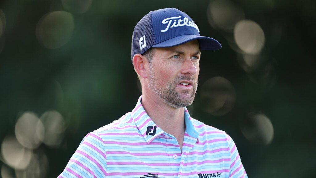webb simpson stares off in the distance in striped shirt at PGA Tour event