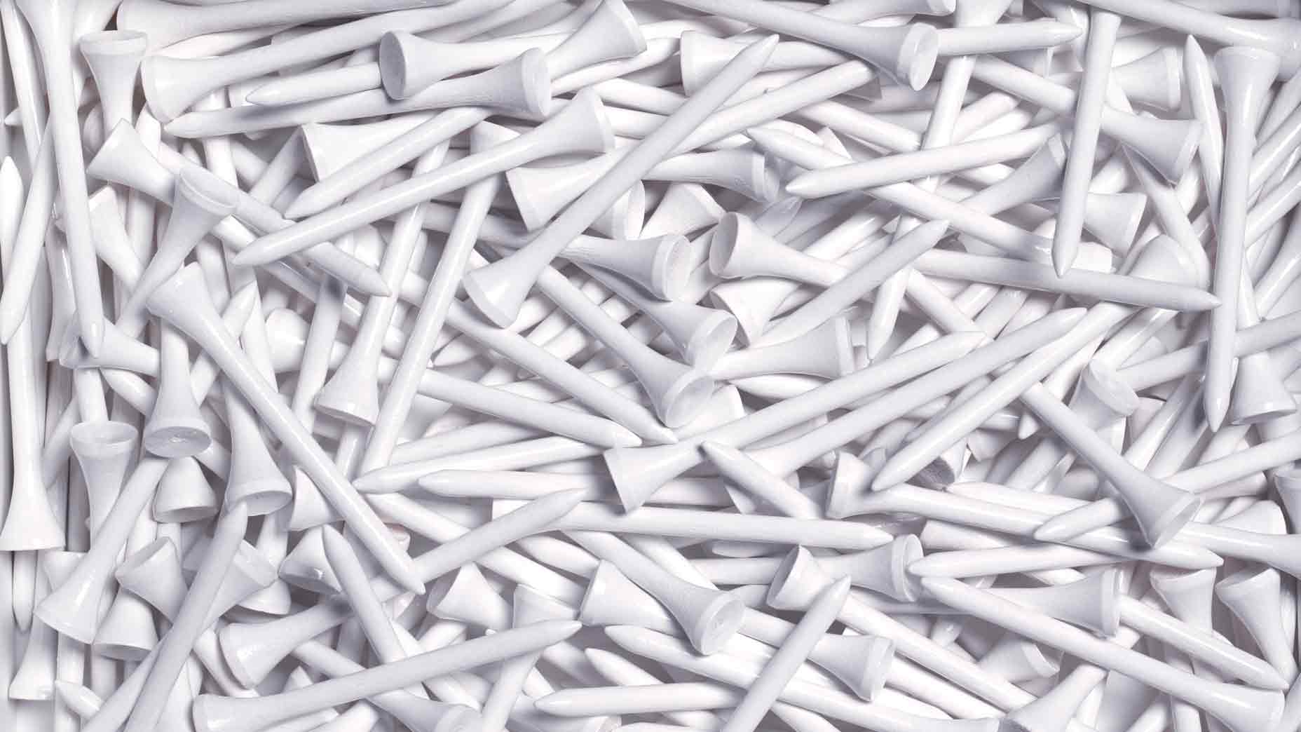 A large pile of white golf tees in a random order
