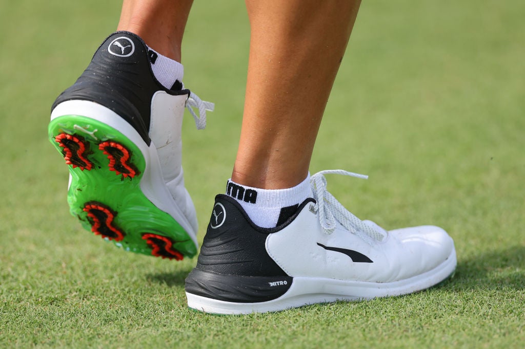 A white and green golf shoe with red spikes.  The latest spike technology from Puma.