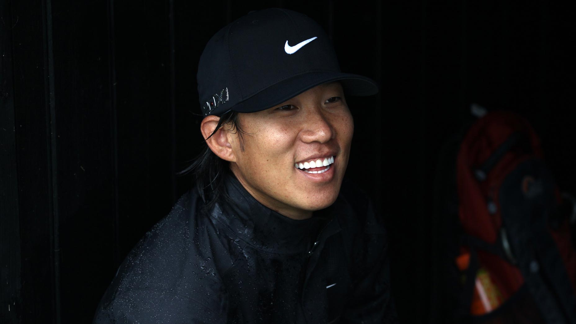 Anthony Kim smiles while hiding from rain at 2011 Open Championship