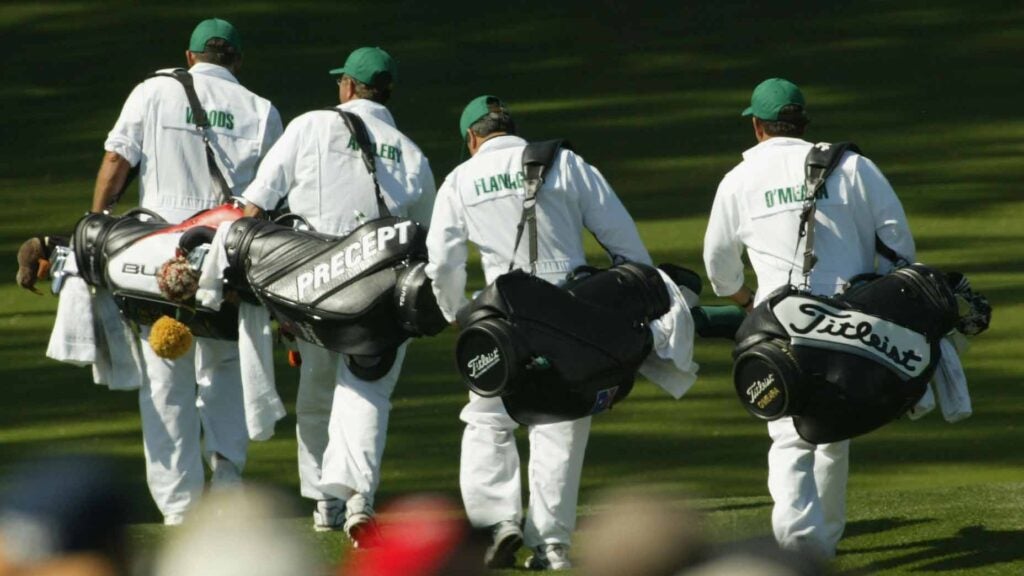 caddies walk with bags on their shoulders during the 2004 masters