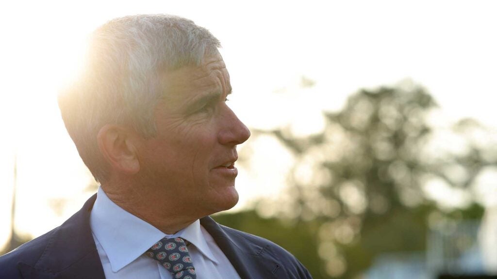 jay monahan wearing a suit stares at the players championship