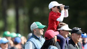 A masters patron watches through binoculars