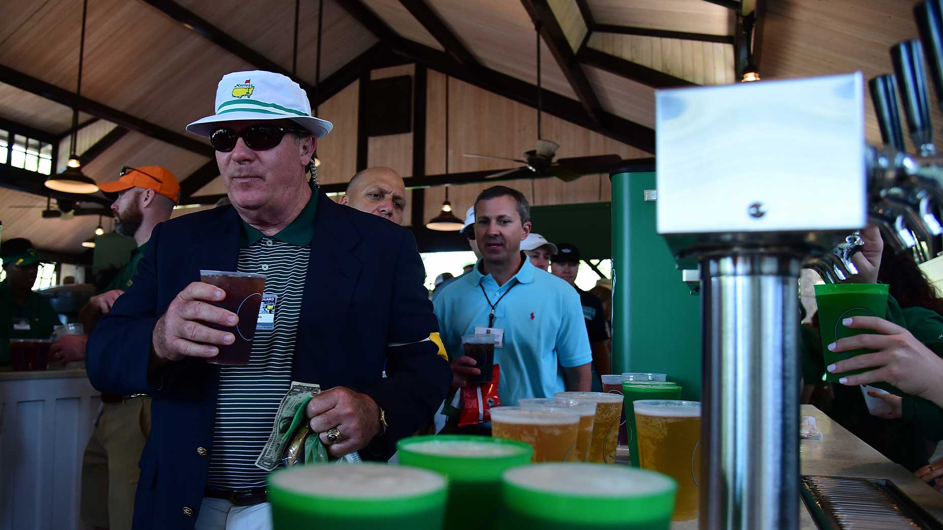 fan purchases beer at the Masters in concession area with hat