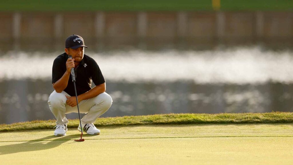 xander schauffele crouches to read a putt during the third round of the 2024 players championship