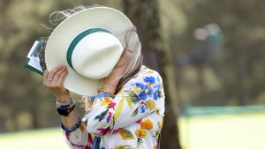 A patron shields herself with her hat from the wind on the 17th hole during the second round of the 2024 Masters Tournament at Augusta National Golf Club