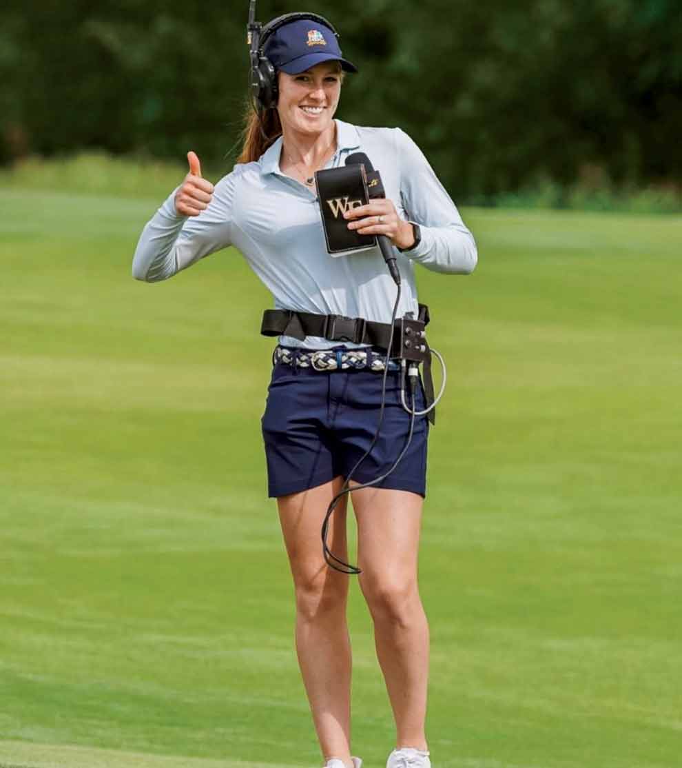 emilia migliaccio gives the camera a thumbs up while wearing broadcasting equipment