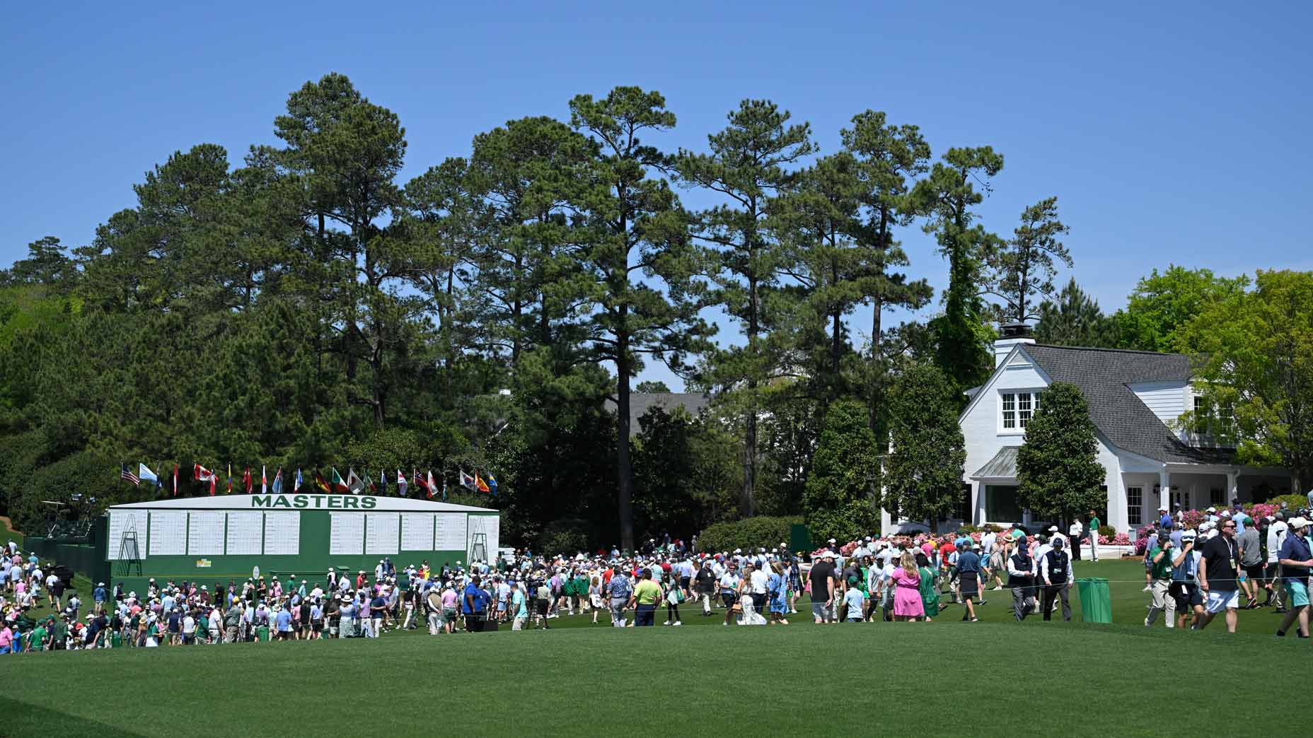 patrons walk in front of the scoreboard during the 2024 masters