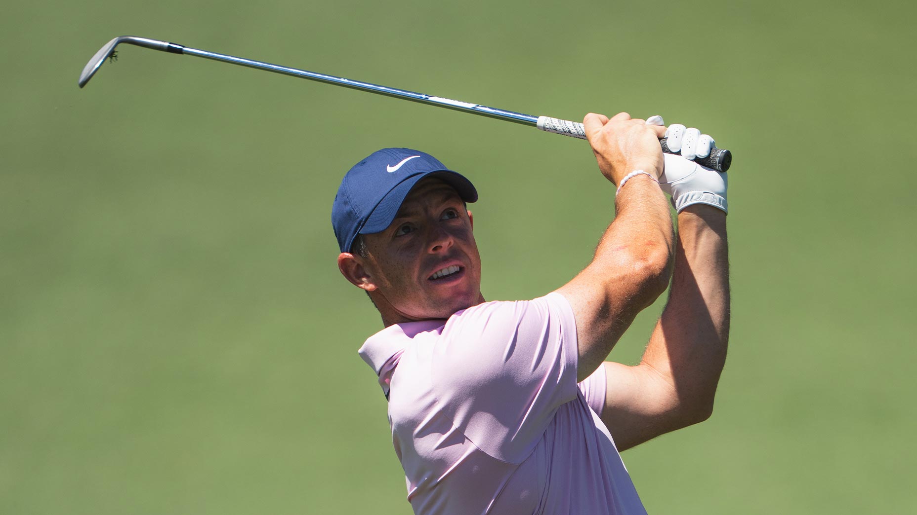 rory mcilroy swings wedge shot at the Masters in a lilac shirt