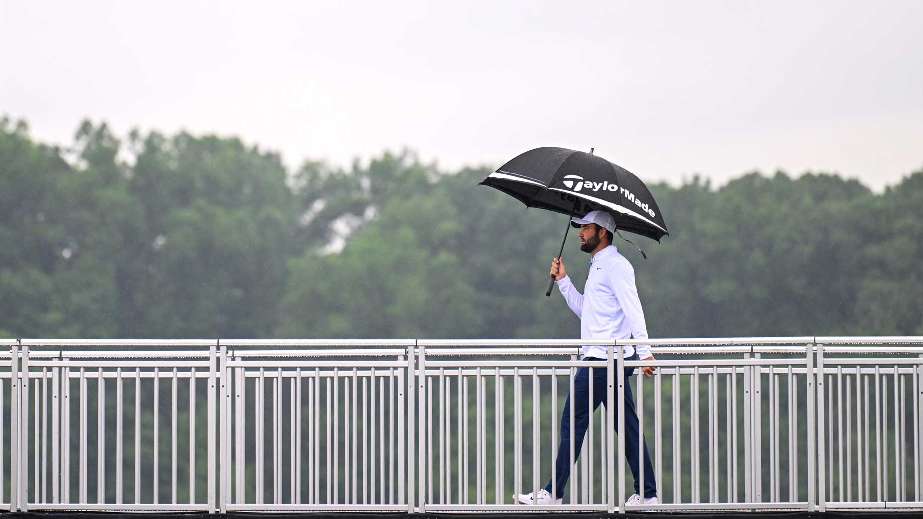 Scottie Scheffler walks across a bridge at the PGA