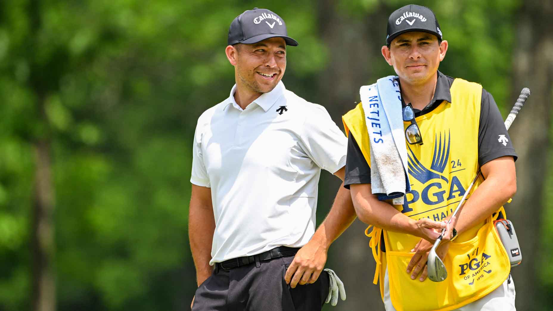 Xander Schauffele smiles with his caddie Austin Kaiser on the eighth hole green during the first round of the 106th PGA Championship at Valhalla Golf Club on May 16, 2024 in Louisville, Kentucky.