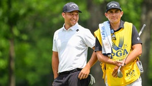 Xander Schauffele smiles with his caddie Austin Kaiser on the eighth hole green during the first round of the 106th PGA Championship at Valhalla Golf Club on May 16, 2024 in Louisville, Kentucky.