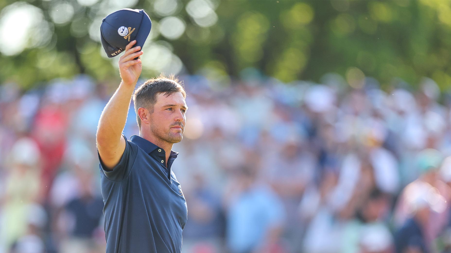 bryson dechambeau tips cap in navy hat at the PGA Championship.