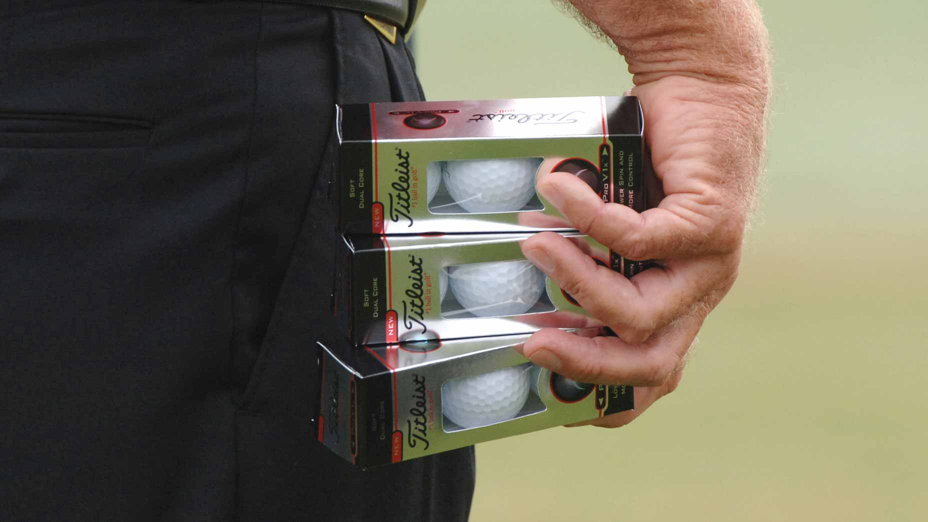 Golfer holding a sleeve of golf balls in hand