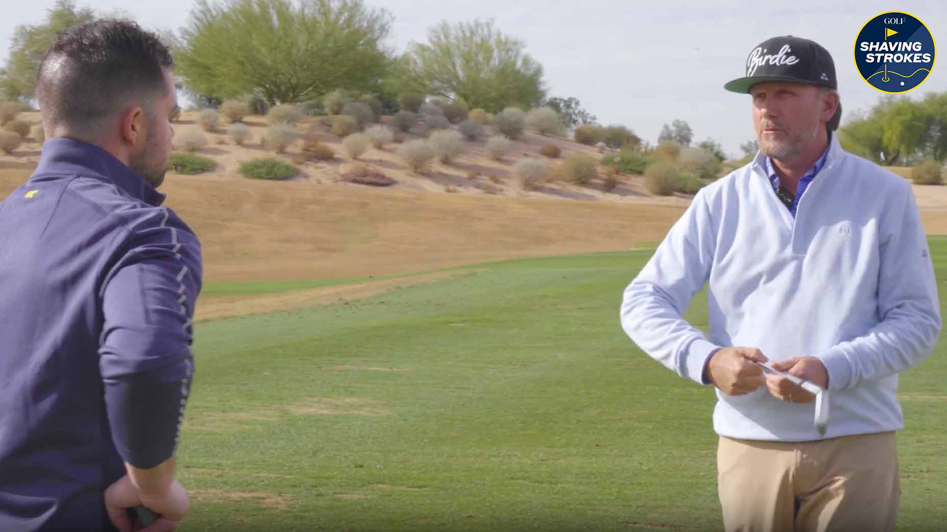 Golf instructor explains tip to student on golf course