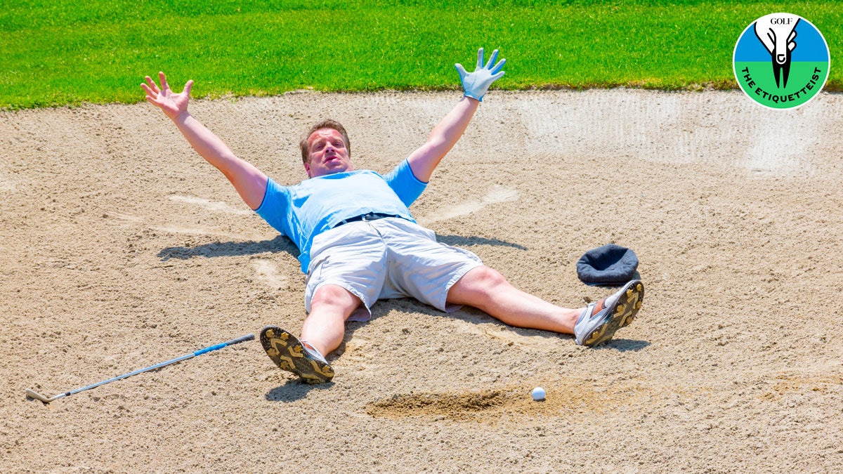 golfer lying in bunker with arms in air