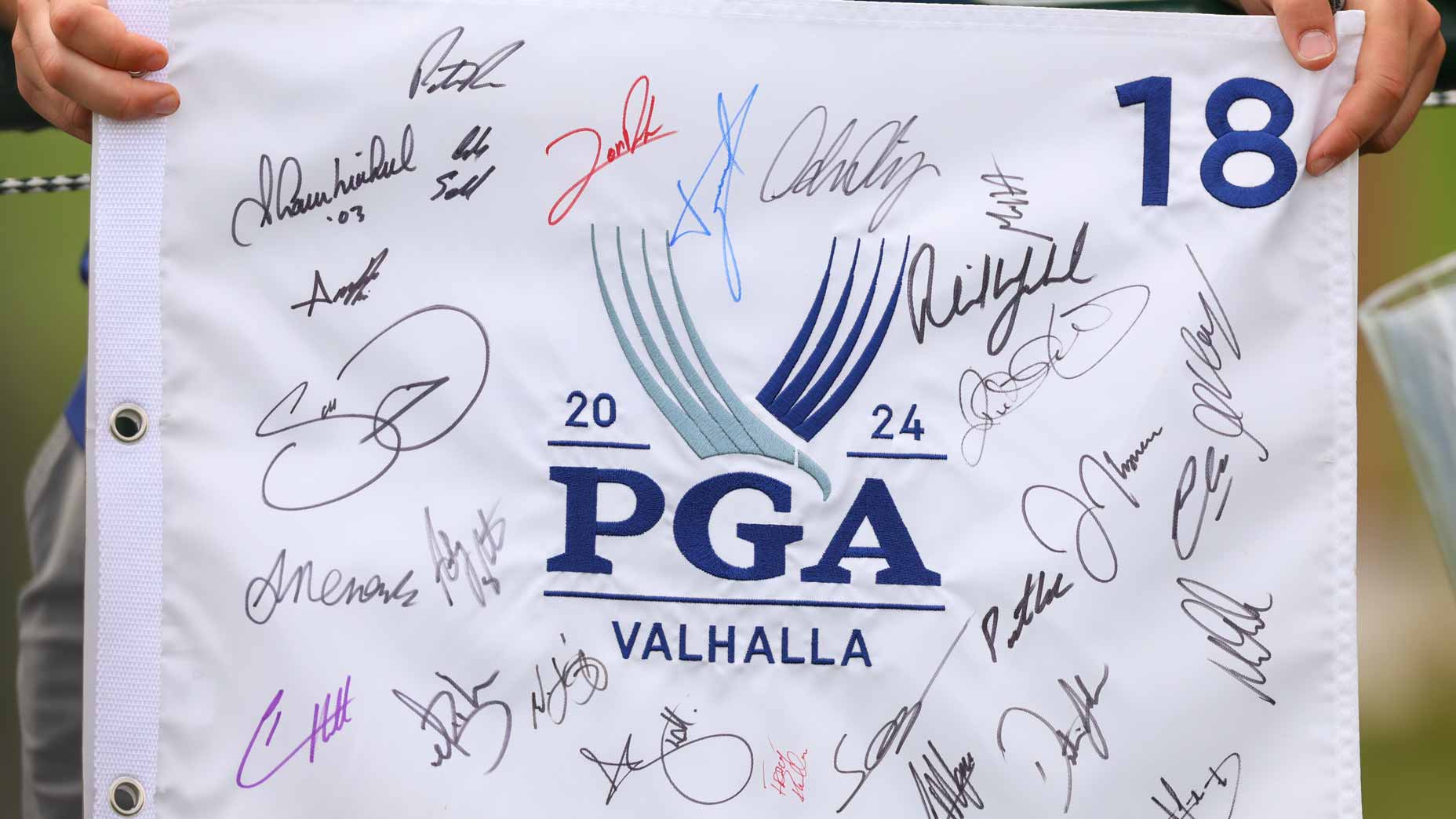 Fans hold signed 2024 PGA Championship flags at Valhalla