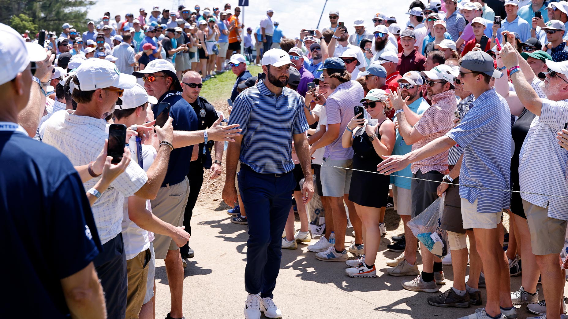 Scottie Scheffler walks through a crowd at the PGA Championship in a striped shirt