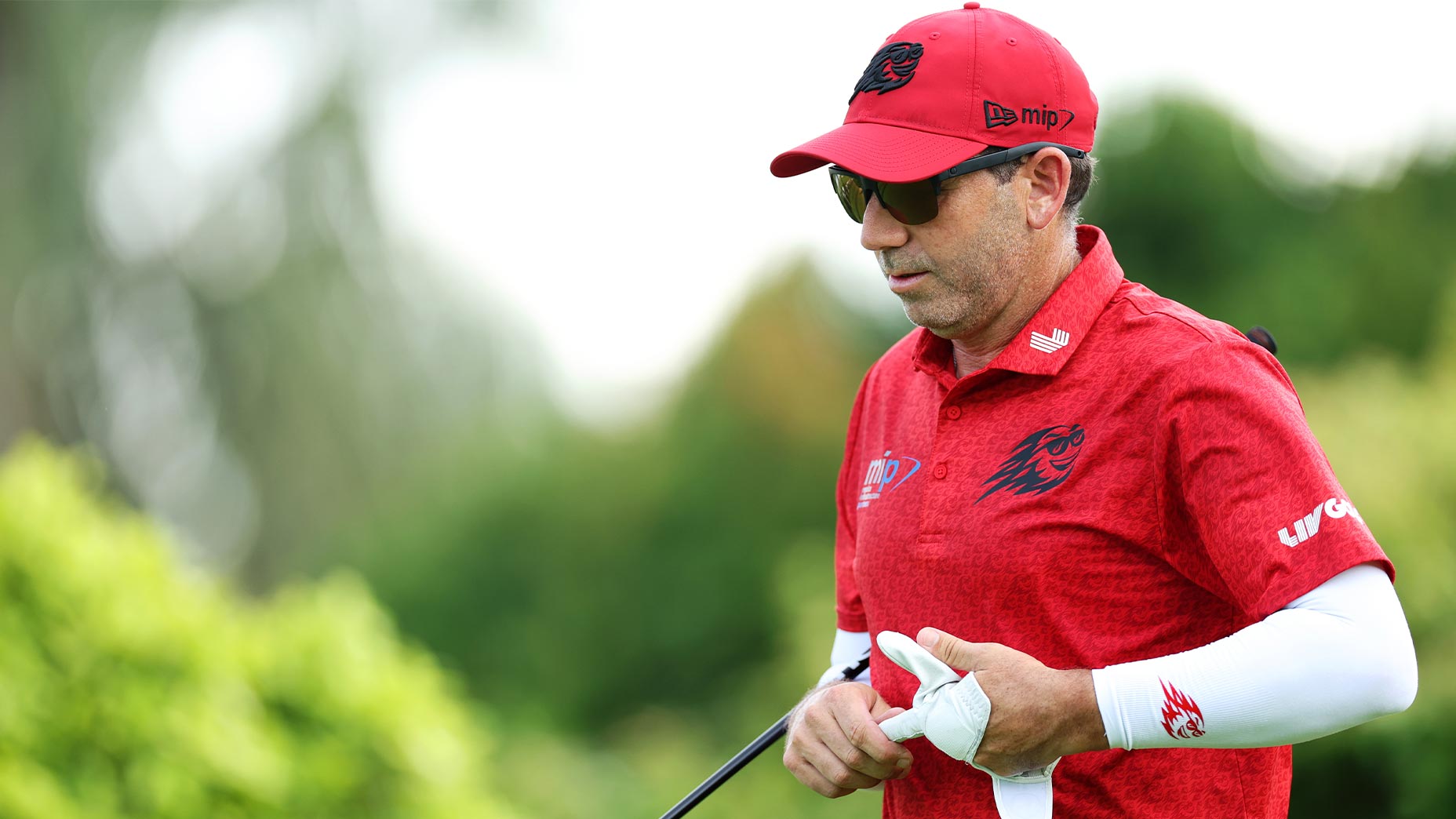 sergio garcia pulls glove off of hand in red shirt and hat