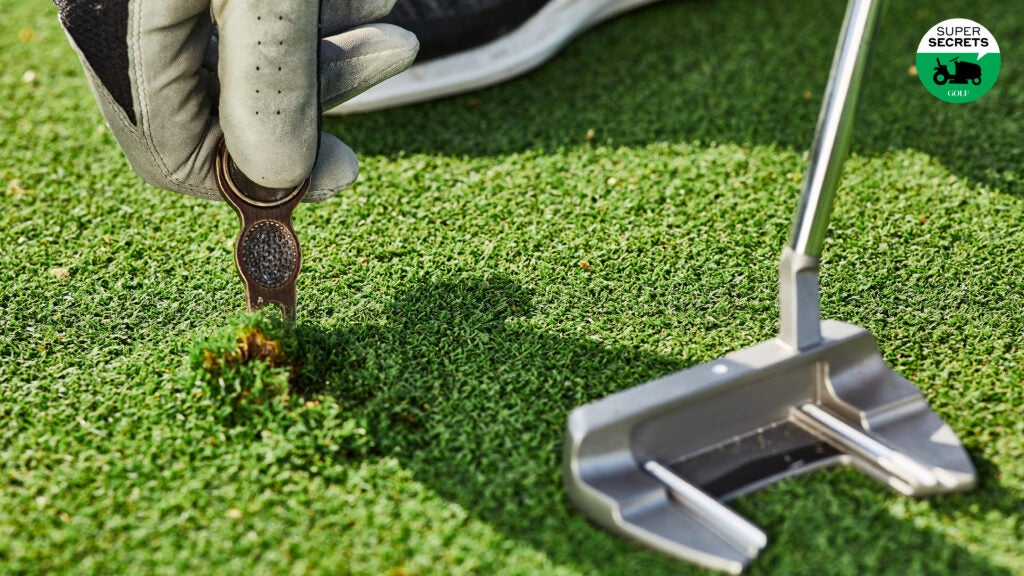 A golfer repairing a ball mark with a divot tool