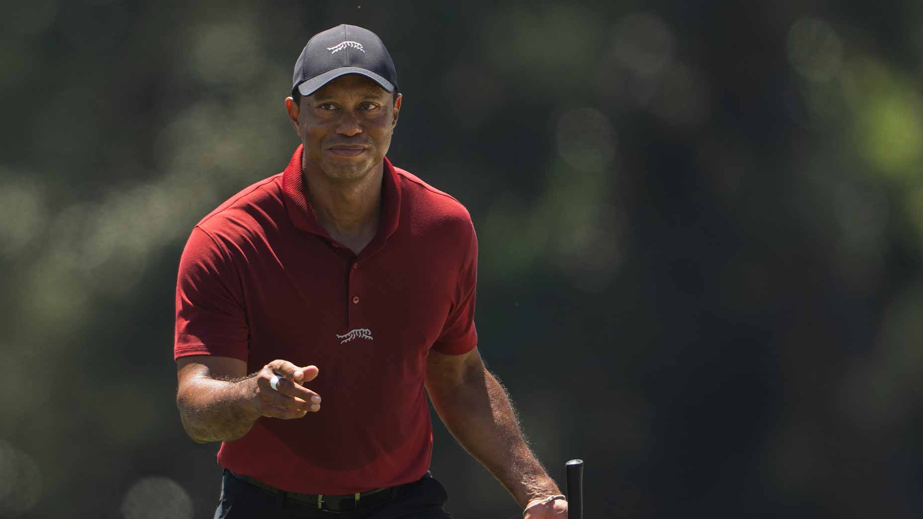 tiger woods waves at the masters tournament in red shirt