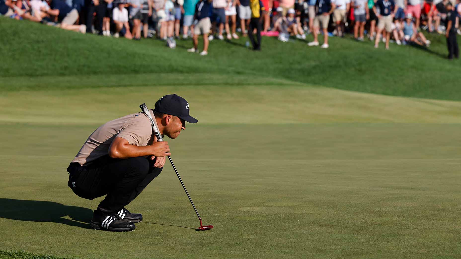 Pro golfer Xander Schauffele crouches to read his PGA-winning putt at Valhalla Golf Club.