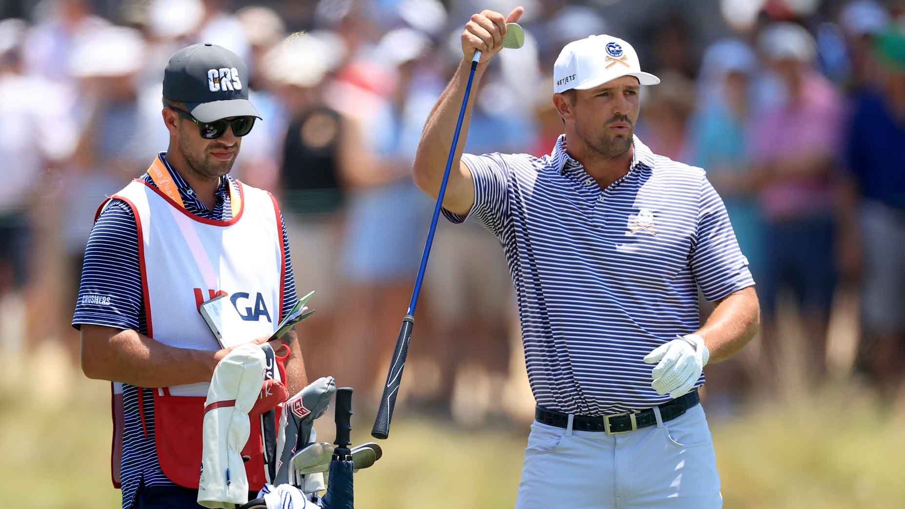 Bryson DeChambeau of the United States pulls a club from his bag alongside caddie Gregory Bodine as they stand on the 18th fairway during the second round of the 124th U.S. Open at Pinehurst Resort on June 14, 2024 in Pinehurst, North Carolina.