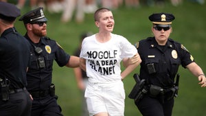 Police lead away a protestor at the Travelers Championship.