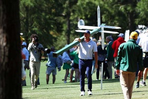 bryson dechambeau carries a sign at the masters