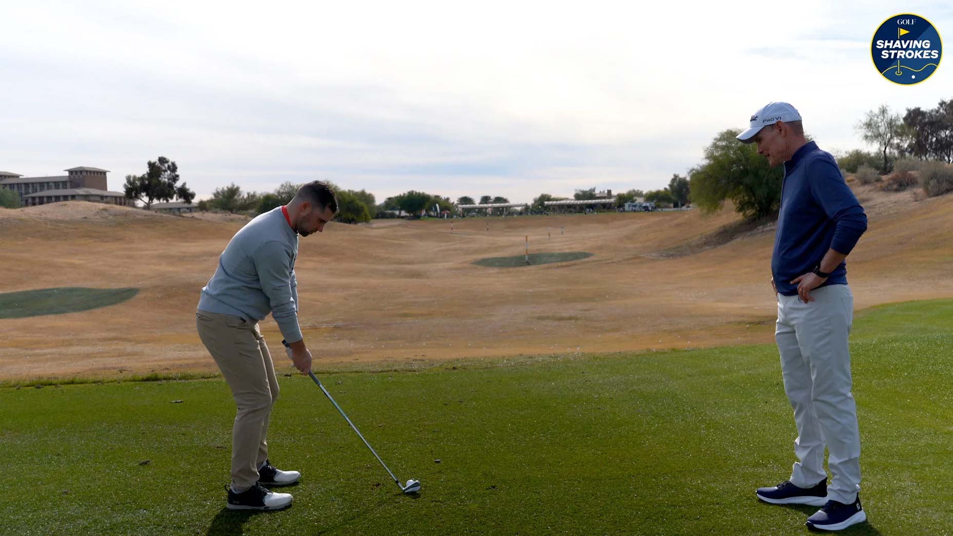 Golf instructor teaches golfer on driving range