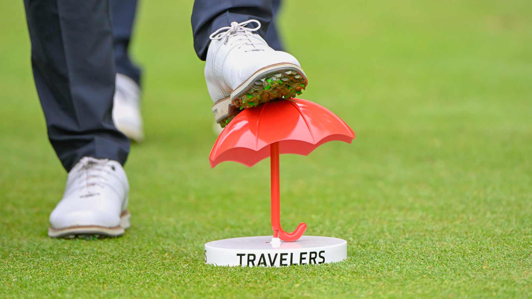Pro golfer rests foot on Travelers Championship tee marker