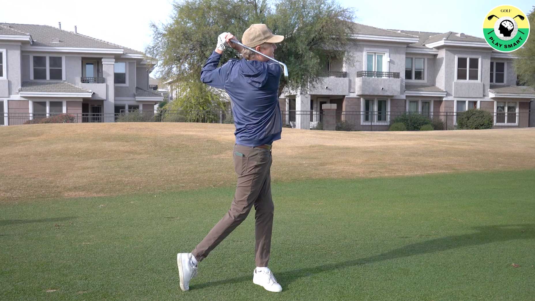 a golfer watches an approach shot