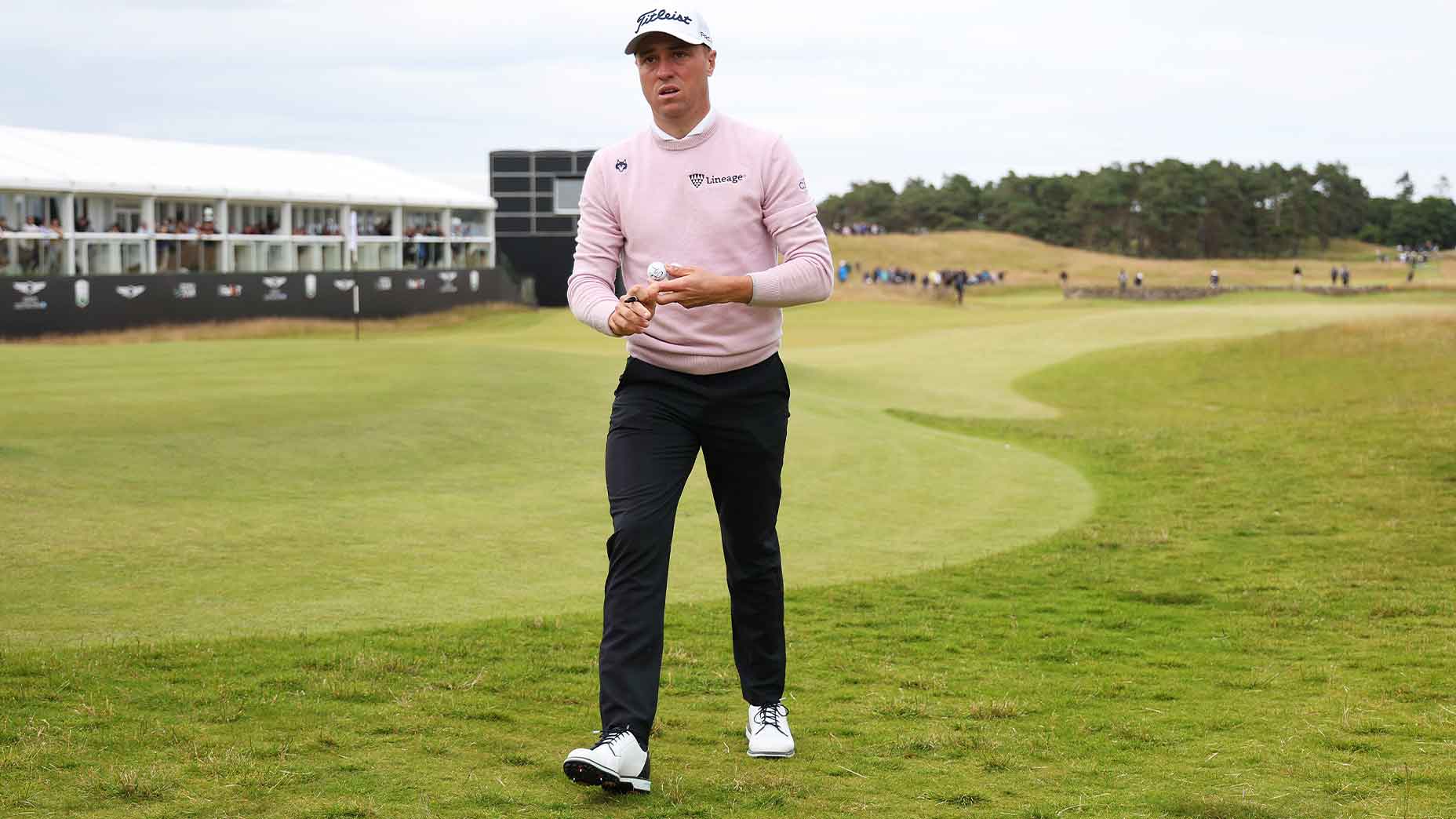 justin thomas walks in genesis scottish wearing a pink shirt