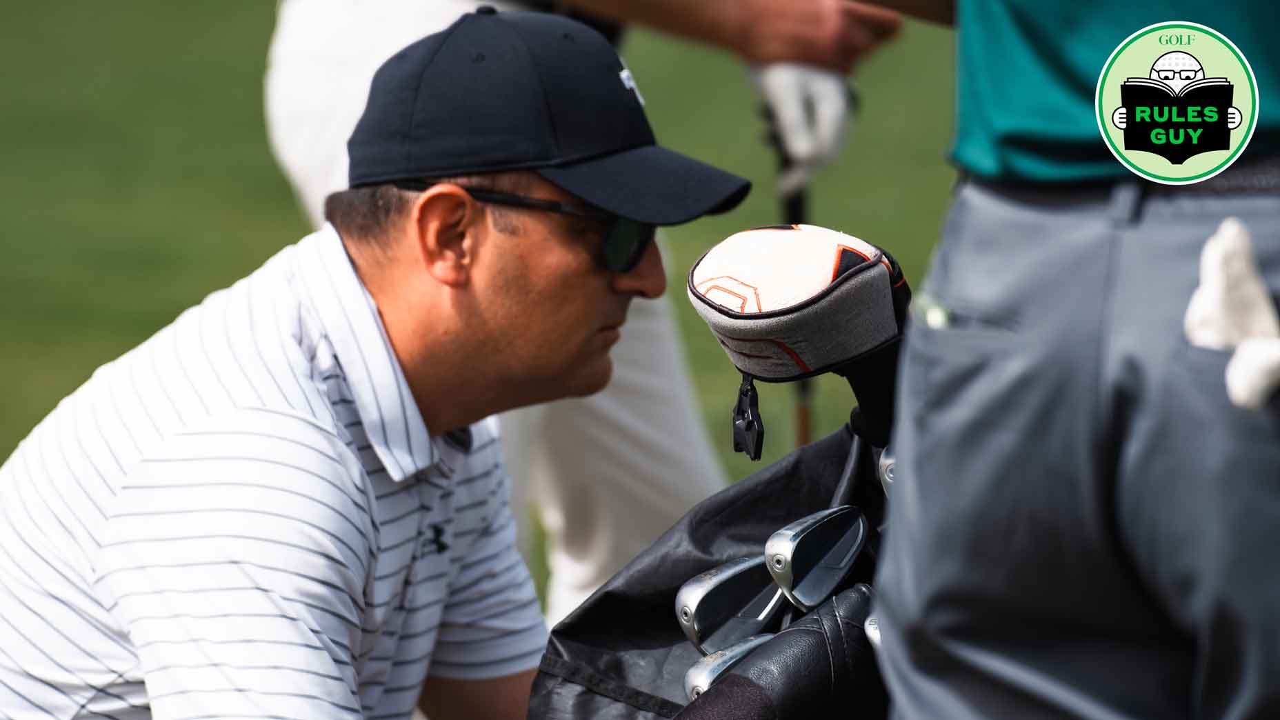 A man studies his clubs before teeing off