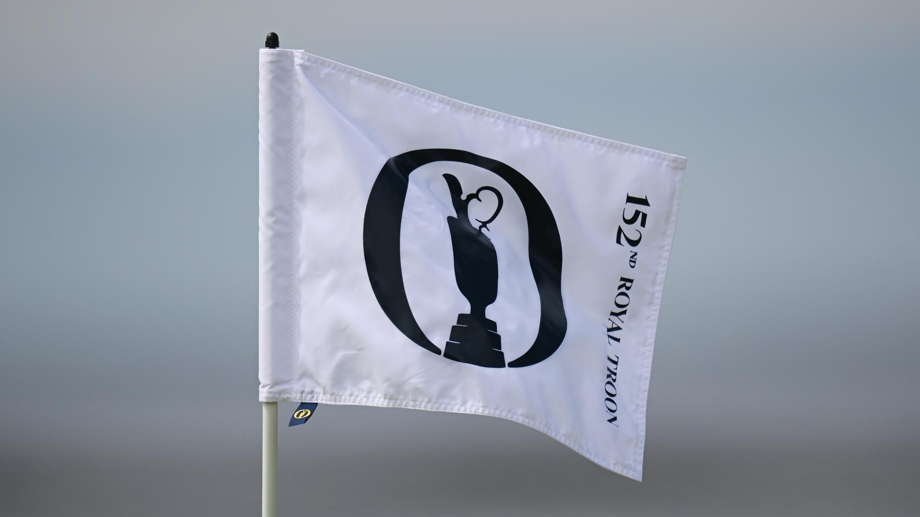 A white 2024 Open Championship flag flies with overcast skies behind it at Royal Troon