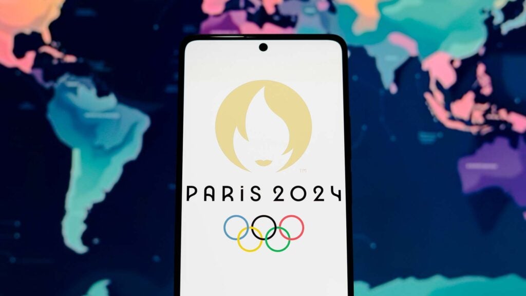 A phone displaying the 2024 Paris Olympics logo in front of a world map.