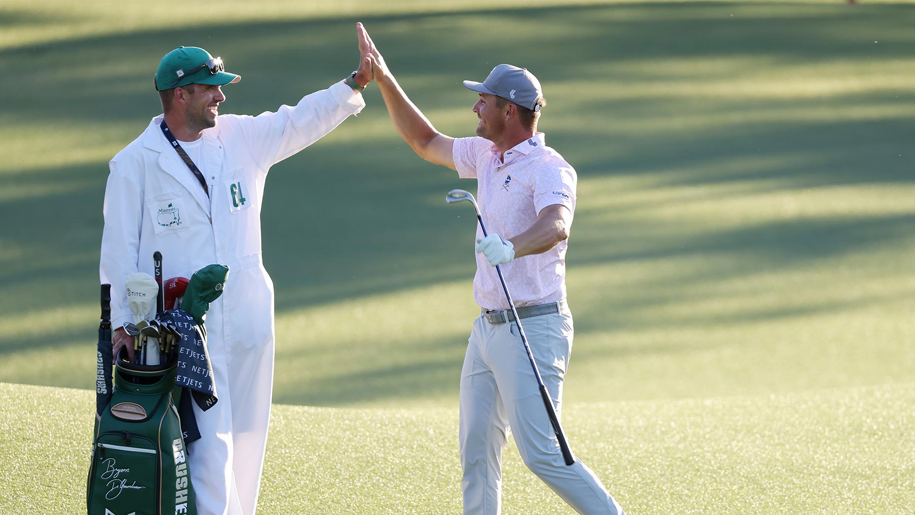 bryson dechambeau and greg bodine high five from the fairway at the masters tournament