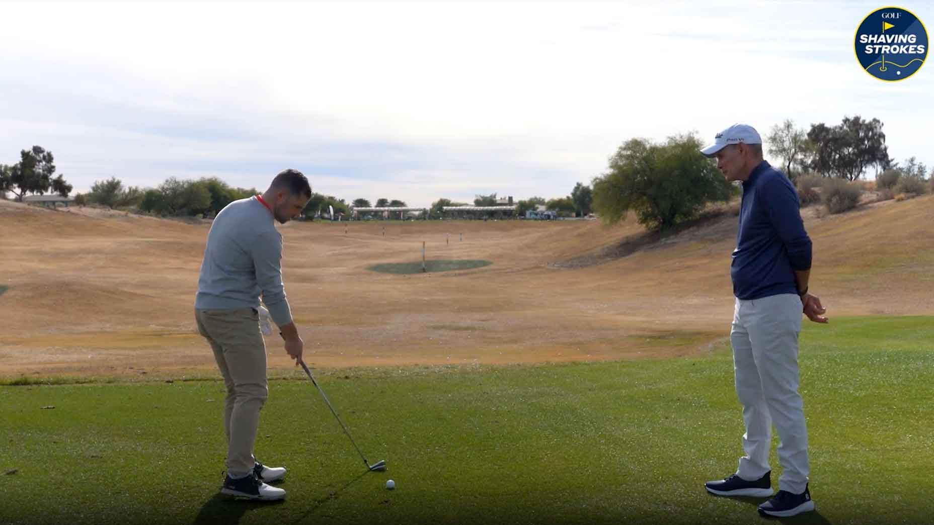 Golf Instructor helps golfer with aim on golf course.