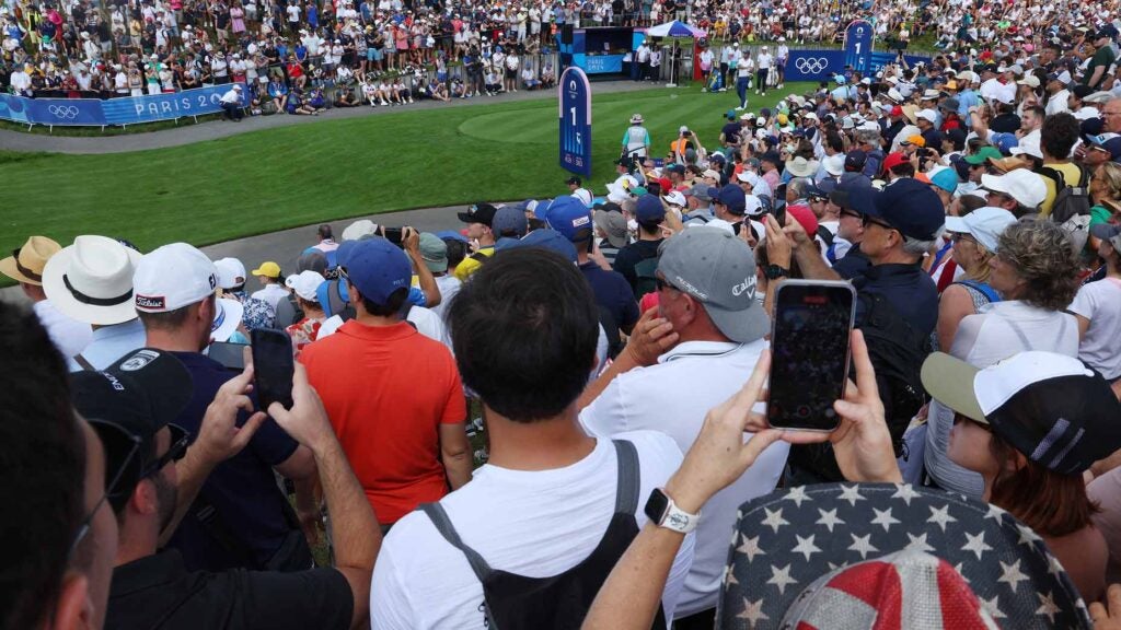 Fans at Le Golf National watch American Scottie Scheffler tee off at 2024 Olympics.