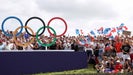 Olympic golf fans cheer in front of Olympic rings at Le Golf National
