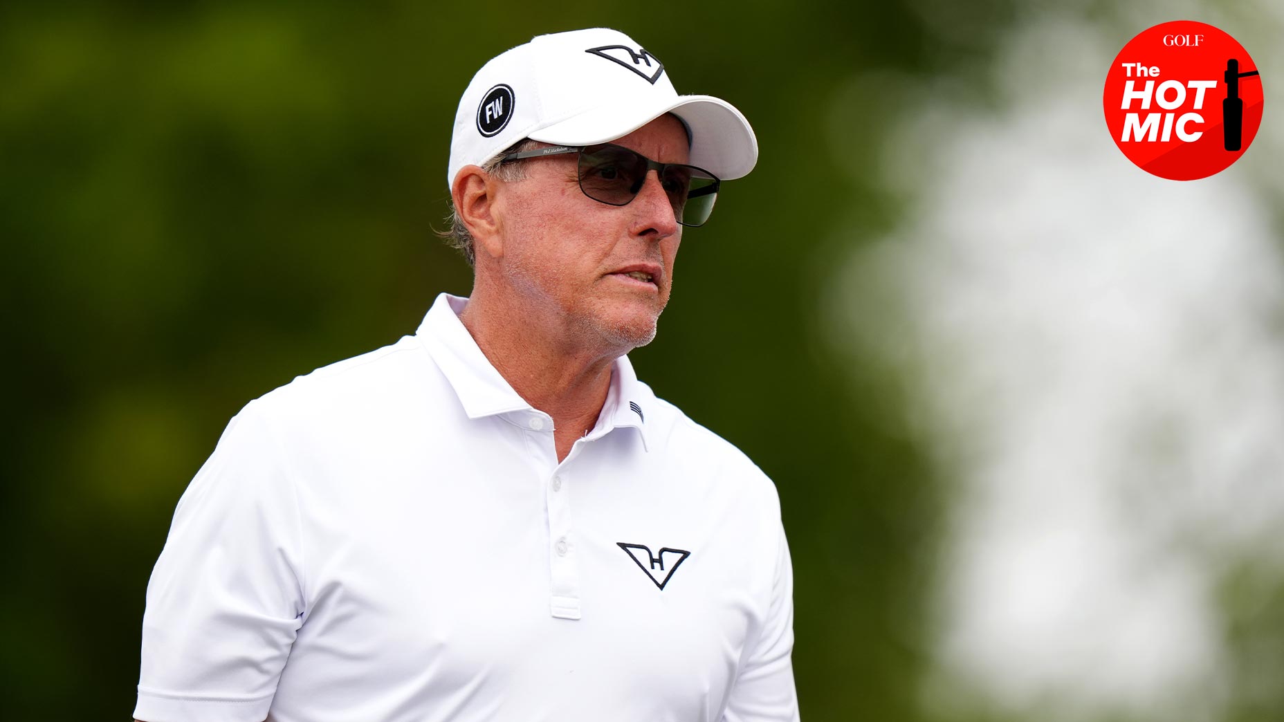 phil mickelson stares at the LIV Golf UK event in a white shirt and white hat and sungalsses