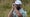 jon rahm looks through rangefinder at the Open Championship in green shirt and white hat