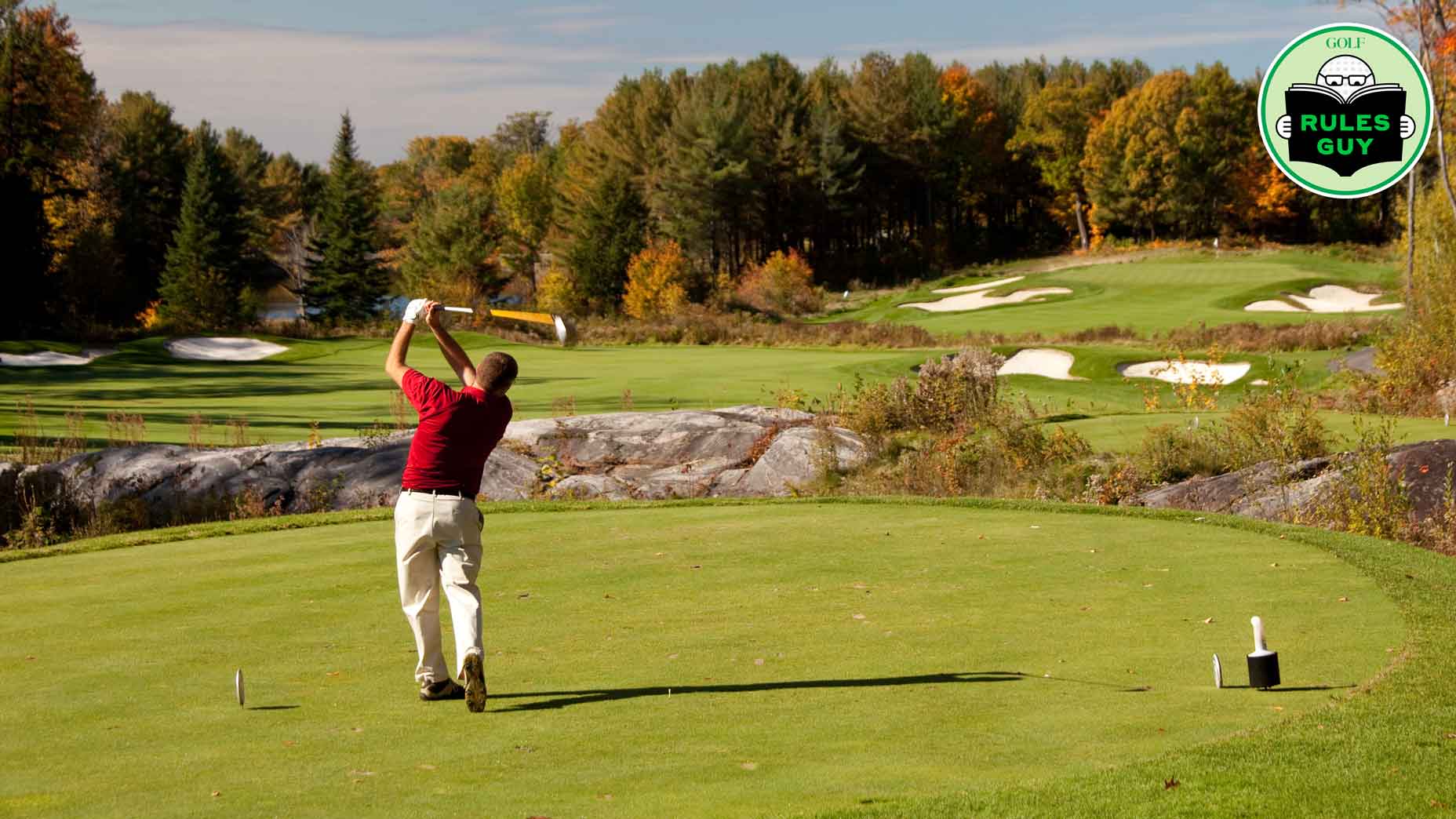 A senior male caucasian golfer driving off a tee box on a beautiful golf course in fall. Muskoka region, Toronto, Ontario, Canada. One golfer is on the tee and demonstrating good form, balance, and skill. Model is unrecognizable and in back view. He is in classic finish position. Beautiful golf hole.